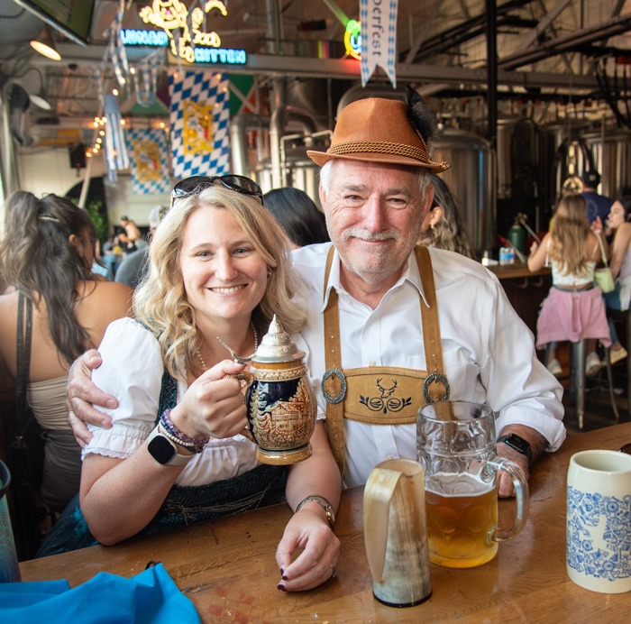 Couple dressed for Oktoberfest toasting with steins