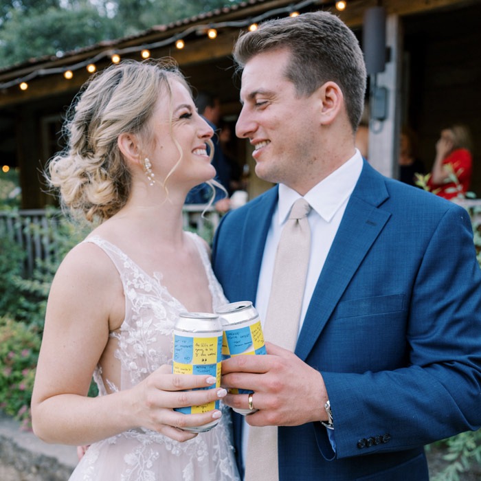 Couple with custom-labeled beer cans for a wedding